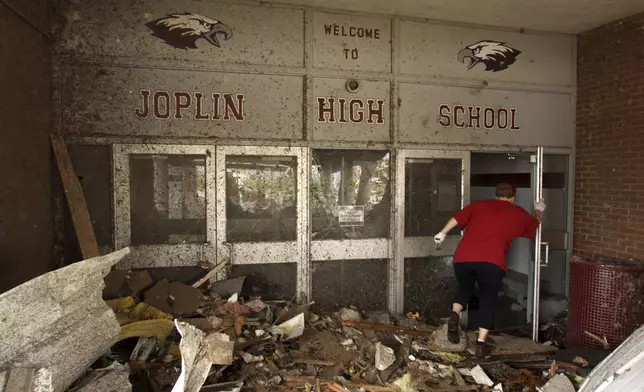 FILE- A woman makes her way into the damaged main entrance of Joplin High School in Joplin, Mo., Tuesday, May 24, 2011. (AP Photo/Mark Schiefelbein, File)