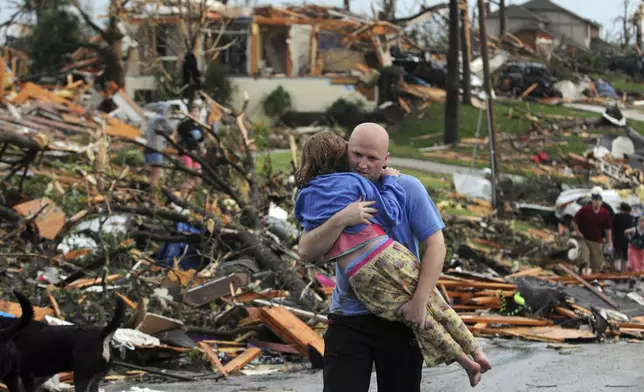 FILE- In this May 22, 2011 file photo, a man carries a young girl who was rescued after a tornado hit Joplin, Mo. (AP Photo/Mike Gullett, File)