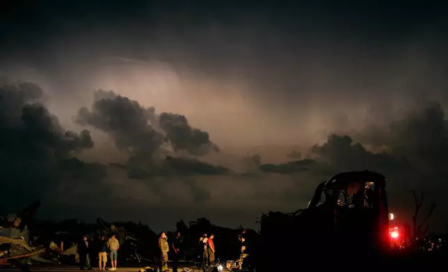 FILE- Emergency workers wait for a medical team after finding a body in a tornado ravaged car in Joplin, Mo., Monday, May 23, 2011. (AP Photo/Charlie Riedel, File)