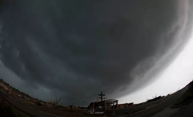 FILE- A cross stands atop a church that was severely damaged by a tornado in Joplin, Mo., as a severe storm passes overhead Monday, May 23, 2011. (AP Photo/Charlie Riedel, File)