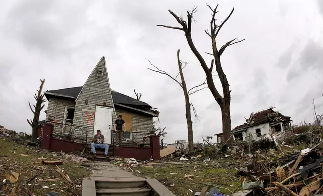 FILE- Bruce Hawkins, sitting, and his stepson James Hurst take a break from clean up at his moderately damaged home in a heavily devastated Joplin neighborhood Wednesday, May 25, 2011. (AP Photo/Charlie Riedel, File)