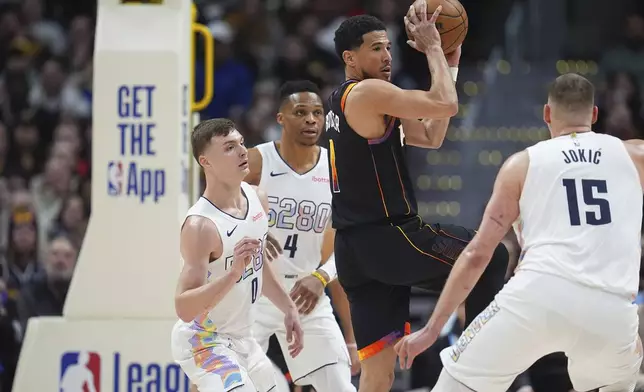 Phoenix Suns guard Devin Booker, third from left, passes the ball as, from left, Denver Nuggets guards Christian Braun and Russell Westbrook and center Nikola Jokic defend in the first half of an NBA basketball game Friday, March 7, 2025, in Denver. (AP Photo/David Zalubowski)