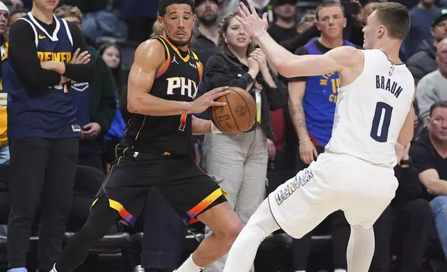 Phoenix Suns guard Devin Booker, left, collects a loose ball as Denver Nuggets guard Christian Braun defends in overtime of an NBA basketball game Friday, March 7, 2025, in Denver. (AP Photo/David Zalubowski)