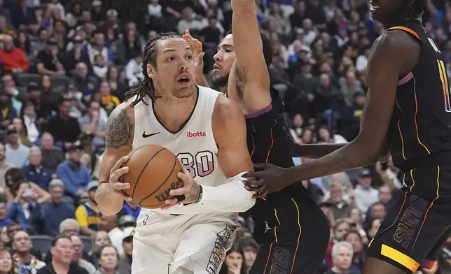 Denver Nuggets forward Aaron Gordon, left, drives past Phoenix Suns guard Devin Booker, center, and center Bol Bol, right, in the first half of an NBA basketball game Friday, March 7, 2025, in Denver. (AP Photo/David Zalubowski)