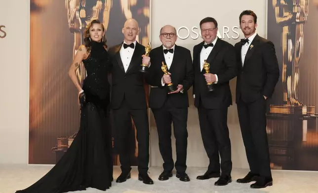 Miley Cyrus, left, and Miles Teller, right, pose with Gareth John, second from left, Richard King, and Ron Bartlett, winners of the award for best sound for "Dune: Part Two," in the press room at the Oscars on Sunday, March 2, 2025, at the Dolby Theatre in Los Angeles. (Photo by Jordan Strauss/Invision/AP)