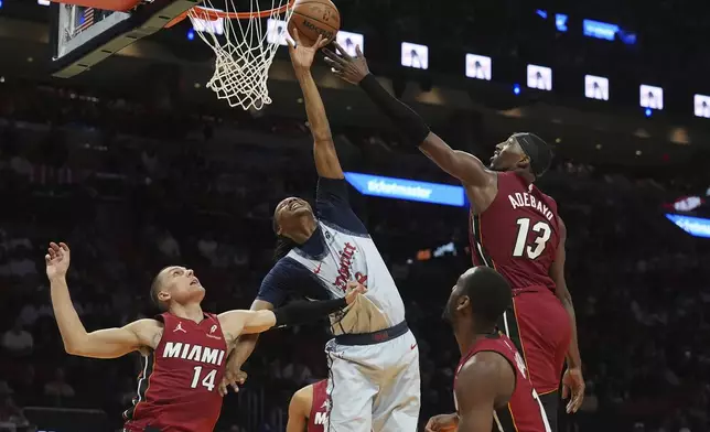 Washington Wizards guard Bub Carrington (8) and Miami Heat center Bam Adebayo (13) grafter a rebound during the first half of an NBA basketball game, Monday, March 3, 2025, in Miami. (AP Photo/Marta Lavandier)