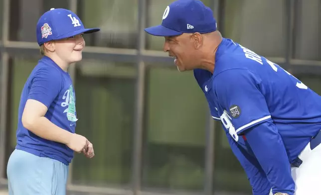 Los Angeles Dodgers manager Dave Roberts chats with a young Dodgers fan during a spring training baseball practice, Friday, Feb. 28, 2025, in Phoenix. (AP Photo/Darryl Webb)
