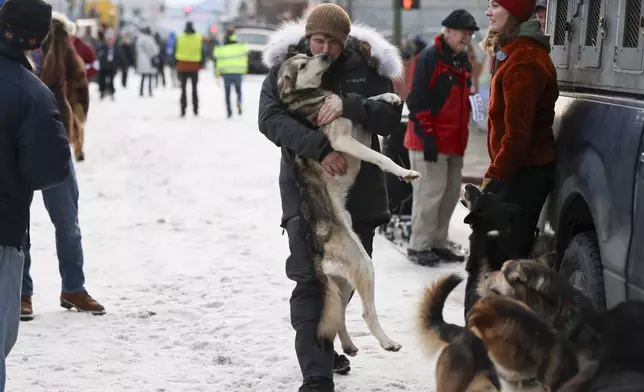 Riley Dyche (17), of Big Lake, Alaska, kisses his sled dog Redoubt while carrying him back to the truck before the Ceremonial Start of the Iditarod Trail Sled Dog Race in Anchorage, Alaska., Saturday, March 1, 2025. (AP Photo/Amanda Loman)