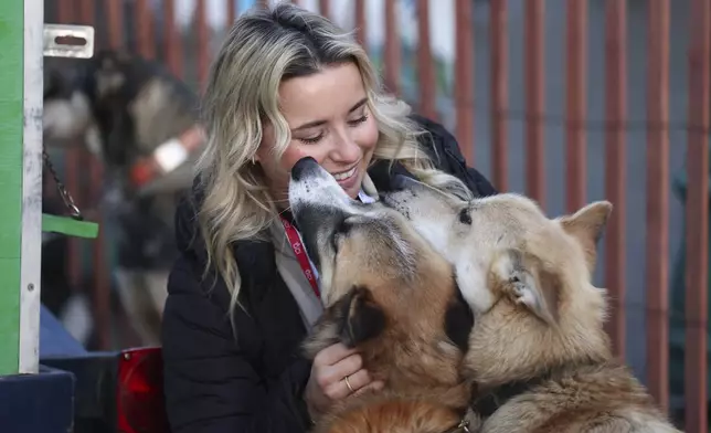 Stephanie Jones, of San Diego, Calif., visits with sled dogs on the team of Justin Olnes (29), of Fairbanks, Alaska, before riding with Olnes in the Ceremonial Start of the Iditarod Trail Sled Dog Race in Anchorage, Alaska., Saturday, March 1, 2025. (AP Photo/Amanda Loman)