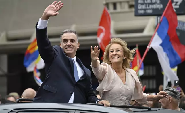 Uruguay's incoming President Yamandu Orsi and Vice President Carolina Cosse wave as they ride in an open car on Inauguration Day, in Montevideo, Uruguay, Saturday, March 1, 2025. (AP Photo/Santiago Mazzarovich)