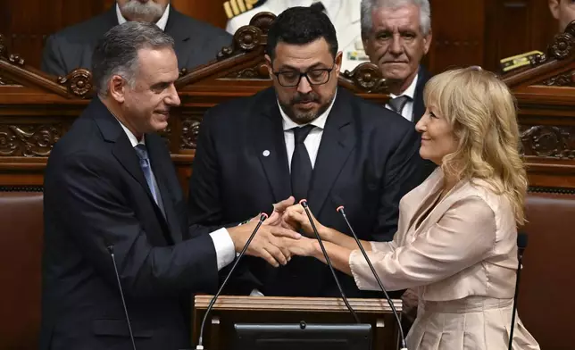 Uruguay's President-elect Yamandu Orsi holds hands with Vice President-elect Carolina Cosse, accompanied by Sen. Alejandro Sanchez, during their swearing-in ceremony in Congress on Inauguration Day, in Montevideo, Uruguay, Saturday, March 1, 2025. (AP Photo/Santiago Mazzarovich)