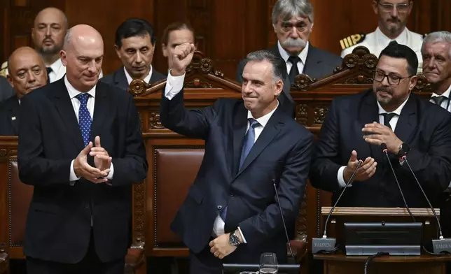 Uruguay's new President Yamandu Orsi raises his right fist during his swearing-in ceremony in Congress, on Inauguration Day in Montevideo, Uruguay, Saturday, March 1, 2025. (AP Photo/Santiago Mazzarovich)