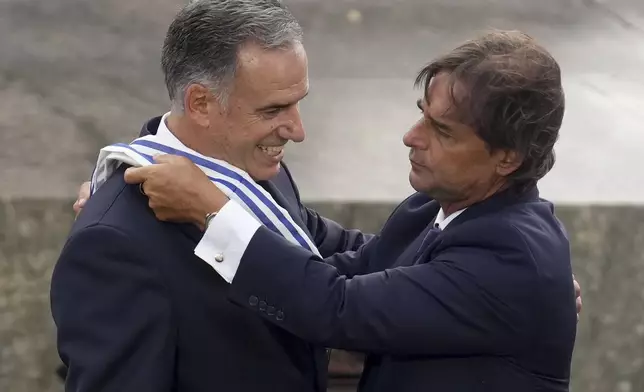 Uruguay's outgoing President Luis Lacalle Pou, right, places the presidential sash on incoming President Yamandu Orsi, on Inauguration Day in Montevideo, Uruguay, Saturday, March 1, 2025. (AP Photo/Matilde Campodonico)