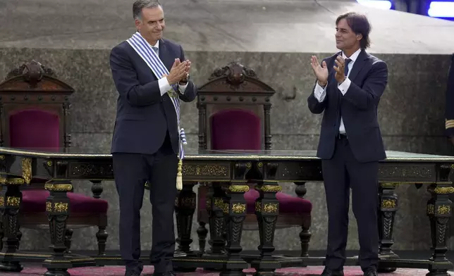 Uruguay's incoming President Yamandu Orsi, left, shows his appreciation after receiving the presidential sash from outgoing President Luis Lacalle Pou, on Inauguration Day in Montevideo, Uruguay, Saturday, March 1, 2025. (AP Photo/Matilde Campodonico)
