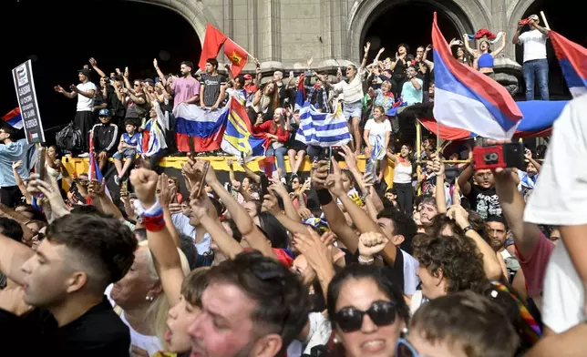 People greet Uruguay's newly sworn-in President Yamandu Orsi and Vice President Carolina Cosse as they ride past in an open car, on Inauguration Day in Montevideo, Uruguay, Saturday, March 1, 2025. (AP Photo/Santiago Mazzarovich)