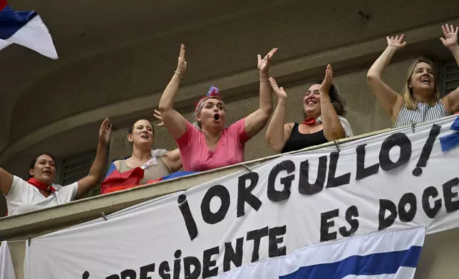 People greet Uruguay's newly sworn-in President Yamandu Orsi and Vice President Carolina Cosse as they ride by in an open car, on Inauguration Day in Montevideo, Uruguay, Saturday, March 1, 2025. (AP Photo/Santiago Mazzarovich)