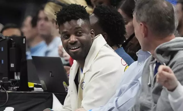 Musician and songwriter Abraham Alexander looks on from the sidelines during the first half of an NBA basketball game between the Memphis Grizzlies and Dallas Mavericks in Dallas, Friday, March 7, 2025. (AP Photo/LM Otero)