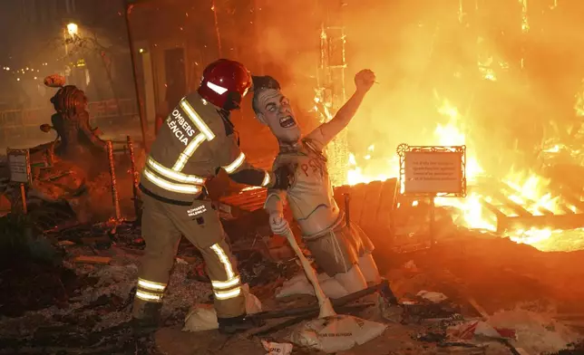A firefights grabs a cardboard sculpture known as a "Ninot" depicting Spain's Prime Minister Pedro Sanchez which didn't burn during the Fallas festival in Valencia, Spain, on Wednesday, March 19, 2025. Five months after deadly floods ravaged Valencia, the Spanish city is hosting its biggest celebration of the year: Las Fallas. Sculptures were built using wreckage from peoples' homes and lampoon politicians accused of mishandling the catastrophe. (AP Photo/Alberto Saiz)