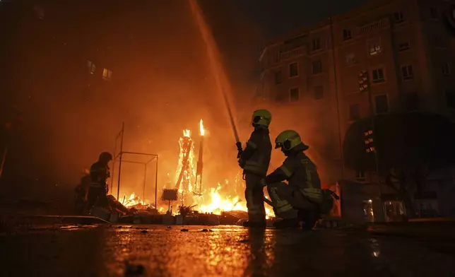 Firefighters put out the remains of the fires in which cardboard sculptures known as "Ninots" burned during the Fallas festival in Valencia, Spain, on Wednesday, March 19, 2025. Five months after deadly floods ravaged Valencia, the Spanish city is hosting its biggest celebration of the year: Las Fallas. Sculptures were built using wreckage from peoples' homes and lampoon politicians accused of mishandling the catastrophe. (AP Photo/Alberto Saiz)