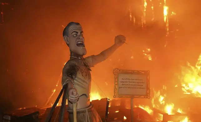 A cardboard sculpture known as a "Ninot" depicting Spain's Prime Minister Pedro Sanchez is engulfed in flames during the Fallas festival in Valencia, Spain, on Wednesday, March 19, 2025. Five months after deadly floods ravaged Valencia, the Spanish city is hosting its biggest celebration of the year: Las Fallas. Sculptures were built using wreckage from peoples' homes and lampoon politicians accused of mishandling the catastrophe. Sign in the Valenciano language reads 'Here we have a recreation of Sanchez falling down on his knees in front of a character who is completely scared.' (AP Photo/Alberto Saiz)