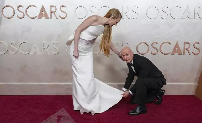 Anna Shevchuk, left, is helped by Yura Borisov as they arrive at the Oscars on Sunday, March 2, 2025, at the Dolby Theatre in Los Angeles. (AP Photo/Jae C. Hong)