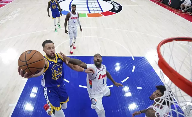 Golden State Warriors' Stephen Curry, left, goes up for a shot against Philadelphia 76ers' Andre Drummond during the first half of an NBA basketball game, Saturday, March 1, 2025, in Philadelphia. (AP Photo/Matt Slocum)