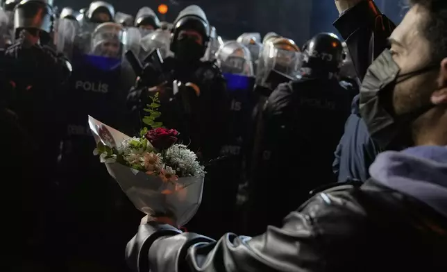 A protester offers flowers to riot police during a protest after Istanbul's Mayor Ekrem Imamoglu was arrested and sent to prison, in Istanbul, Turkey, Tuesday, March 25, 2025. (AP Photo/Khalil Hamra)