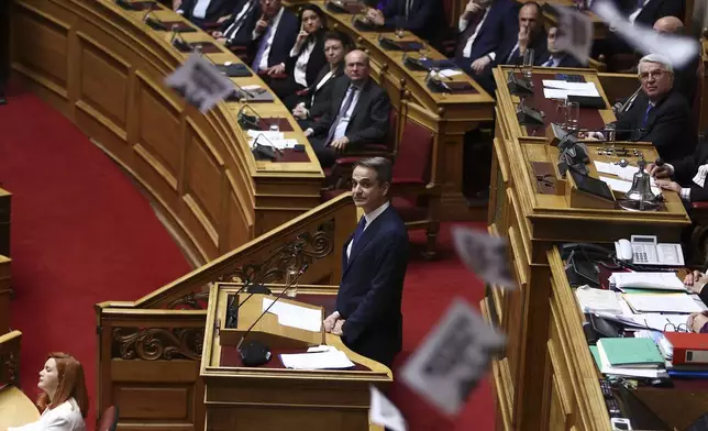 Protesters throw flyers as Greece's Prime Minister Kyriakos Mitsotakis speaks, on the third and final day of a censure motion debate against the conservative government in parliament over a deadly rail disaster nearly two years ago, in Athens, Greece, Friday, March 7, 2025. (Ismini Vlassopoulou/InTime News via AP)