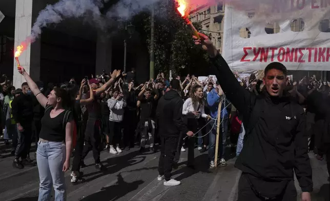 University students hold up flares during a rally, on the third and final day of a censure motion debate against the conservative government in parliament over a deadly rail disaster nearly two years ago, in Athens, Greece, Friday, March 7, 2025. (AP Photo/Thanassis Stavrakis)