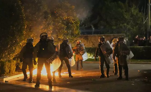 Protesters throw molotov against riot police during clashes, on the third and final day of a censure motion debate against the conservative government in parliament over a deadly rail disaster nearly two years ago, in Athens, Greece, Friday, March 7, 2025. (AP Photo/Petros Giannakouris)