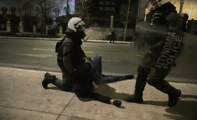 Riot policemen detain a protester during clashes, on the third and final day of a censure motion debate against the conservative government in parliament over a deadly rail disaster nearly two years ago, in Athens, Greece, Friday, March 7, 2025. (AP Photo/Petros Giannakouris)