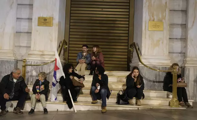 Protesters sit outside luxury hotel during a rally, on the third and final day of a censure motion debate against the conservative government in parliament over a deadly rail disaster nearly two years ago, in Athens, Greece, Friday, March 7, 2025. (AP Photo/Petros Giannakouris)
