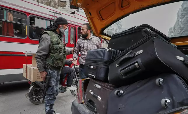 A fighter from the Druze Rijal al-Karameh militia talks to a driver while looking through his car at a checkpoint in the town of Jaramana, in the southern outskirts of Damascus, Syria, March 3, 2025. (AP Photo/Omar Sanadiki)
