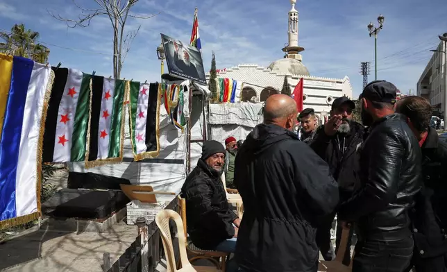 Druze men gather by a newsstand selling flags of Syria and the Druze community at Al Karama Square in city of Sweida, Syria, March 4, 2025.(AP Photo/Omar Sanadiki)