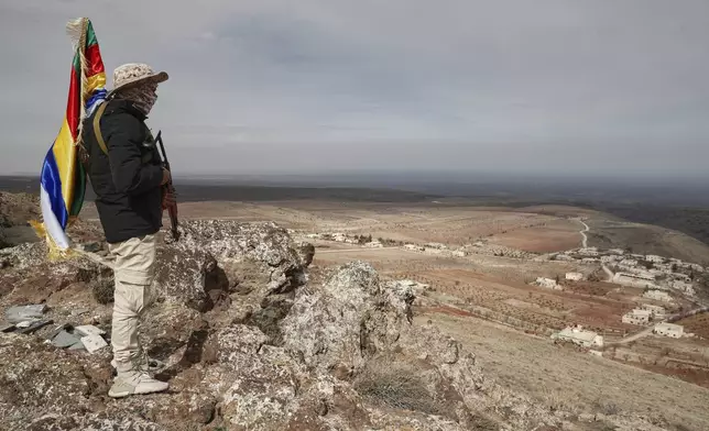 A fighter of the Druze Liwa al-Jabal militia holds an Islamic offshoot's flag as he guards on a hilltop near an outpost in the southern province of Sweida, Syria, March 4, 2025.(AP Photo/Omar Sanadiki)