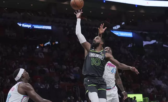 Minnesota Timberwolves guard Mike Conley (10) drives to the basket as Miami Heat guard Davion Mitchell (45) defends during the second half of an NBA basketball game, Friday, March 7, 2025, in Miami. (AP Photo/Marta Lavandier)