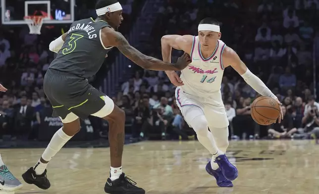 Miami Heat guard Tyler Herro (14) dribbles the ball as Minnesota Timberwolves forward Jaden McDaniels (3) defends during the first half of an NBA basketball game, Friday, March 7, 2025, in Miami. (AP Photo/Marta Lavandier)