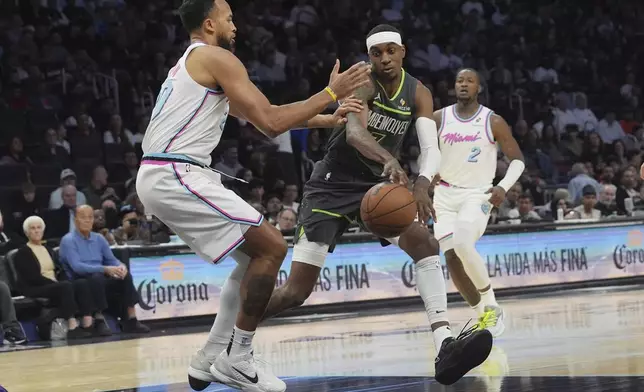 Minnesota Timberwolves forward Jaden McDaniels (3) passes the ball as Miami Heat forward Kyle Anderson (20) defends during the second half of an NBA basketball game, Friday, March 7, 2025, in Miami. (AP Photo/Marta Lavandier)