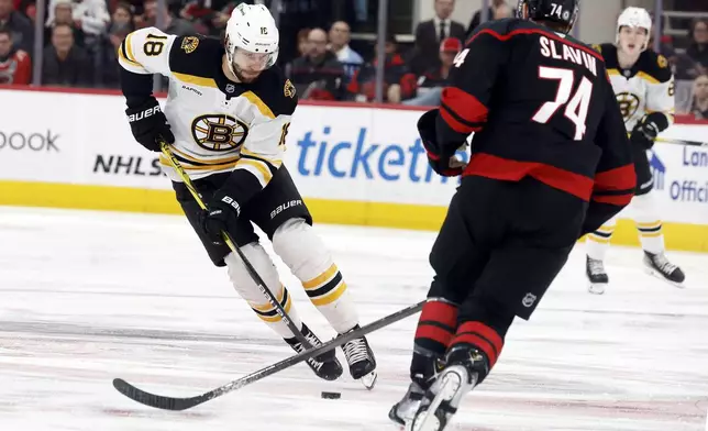 Boston Bruins' Pavel Zacha (18) controls the puck and skates around Carolina Hurricanes' Jaccob Slavin (74) during the first period of an NHL hockey game in Raleigh, N.C., Thursday, March 6, 2025. (AP Photo/Karl DeBlaker)