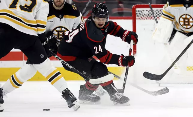 Carolina Hurricanes' Seth Jarvis (24) loses control of the puck to Boston Bruins' Charlie Coyle (13) during the first period of an NHL hockey game in Raleigh, N.C., Thursday, March 6, 2025. (AP Photo/Karl DeBlaker)