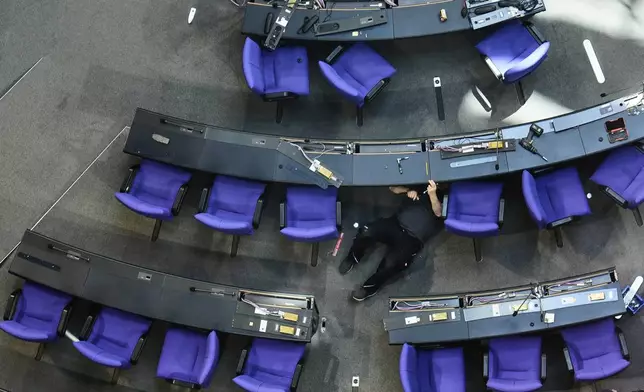 A worker prepares the hall for the new seating of the federal parliament Bundestag at the Reichstag building in Berlin, Germany, Wednesday, March 19, 2025. (AP Photo/Markus Schreiber)
