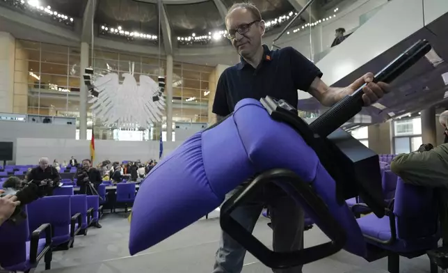 A worker removes a seat during the set-up for the new seating of the federal parliament Bundestag at the Reichstag building in Berlin, Germany, Wednesday, March 19, 2025. (AP Photo/Markus Schreiber)