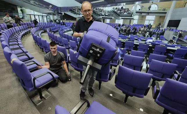 A worker removes a seat during the set-up for the new seating of the federal parliament Bundestag at the Reichstag building in Berlin, Wednesday, March 19, 2025. (AP Photo/Markus Schreiber)