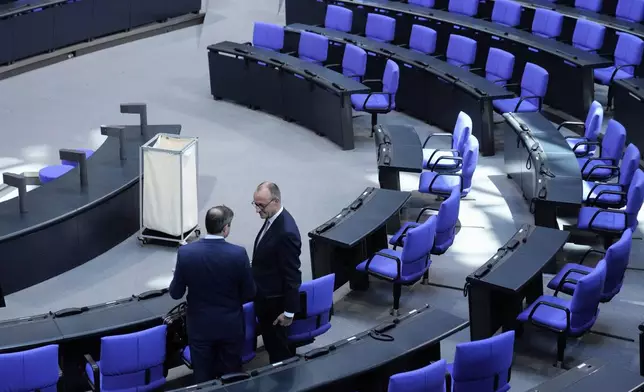 German opposition leader and Christian Democratic Union party chairman Friedrich Merz , right, talks to a law maker after a debate and voting about loosen the country's debt rules and change constitution in the German Parliament Bundestag in Berlin, Germany, Tuesday, March 18, 2025. (AP Photo/Ebrahim Noroozi)