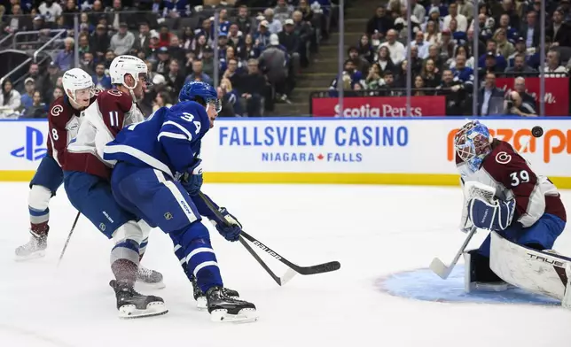 Toronto Maple Leafs' Auston Matthews (34) shoots on Colorado Avalanche goaltender Mackenzie Blackwood (39) while defended by Brock Nelson (11) during the second period of an NHL hockey game in Toronto on Wednesday, March 19, 2025. (Christopher Katsarov/The Canadian Press via AP)