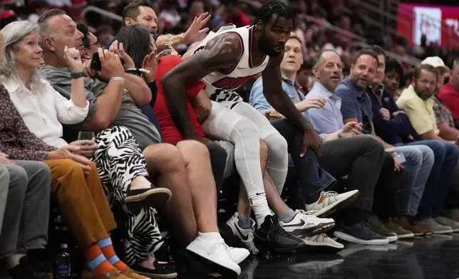 Houston Rockets forward Tari Eason (17) lands on a fan during the first half of an NBA basketball game against the Denver Nuggets in Houston, Sunday, March 23, 2025. (AP Photo/Ashley Landis)