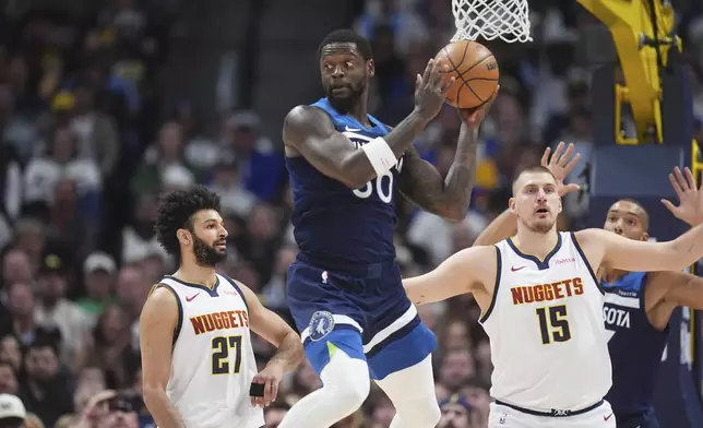 Minnesota Timberwolves forward Julius Randle, center, turns to pass the ball as Denver Nuggets guard Jamal Murray, left, and center Nikola Jokic defend in the first half of an NBA basketball game Wednesday, March 12, 2025, in Denver. (AP Photo/David Zalubowski)