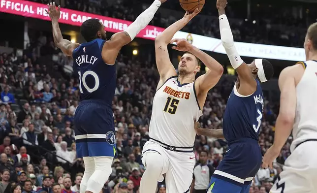 Denver Nuggets center Nikola Jokic, center, drives to the basket between Minnesota Timberwolves guard Mike Conley, left, and forward Jaden McDaniels in the first half of an NBA basketball game Wednesday, March 12, 2025, in Denver. (AP Photo/David Zalubowski)