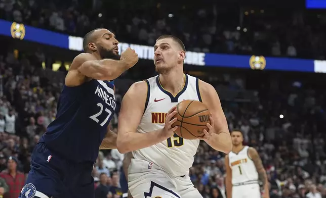 Denver Nuggets center Nikola Jokic, right, drives to the basket as Minnesota Timberwolves center Rudy Gobert defends in the first half of an NBA basketball game Wednesday, March 12, 2025, in Denver. (AP Photo/David Zalubowski)