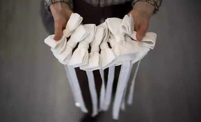 An employee holds bow ties in Lambert Hofer, a renowned costume workshop in Vienna, Austria, Wednesday, Febr 26, 2025. (AP Photo/Denes Erdos)
